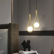 Two elegant gold-toned decorbites™ modern nordic pendant lights with teardrop frames and glowing bulbs hanging from black cords