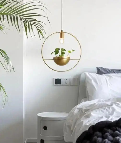Gold-toned circular pendant light with a modern nordic planter featuring a hanging plant in a matching bowl