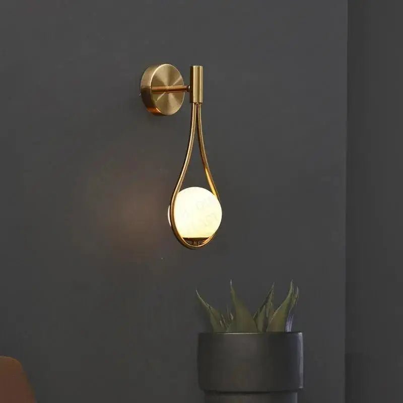 Gold-toned DecorBites™ modern Nordic livi wall lamp with teardrop frame and glowing frosted glass globe