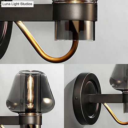 Industrial-style wall sconce lighting fixture with modern smoked glass mushroom shades in black metal and brass accents