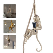 DecorBites metallic gold monkey decoration hanging from hemp rope holding a black rope chandelier lamp fixture
