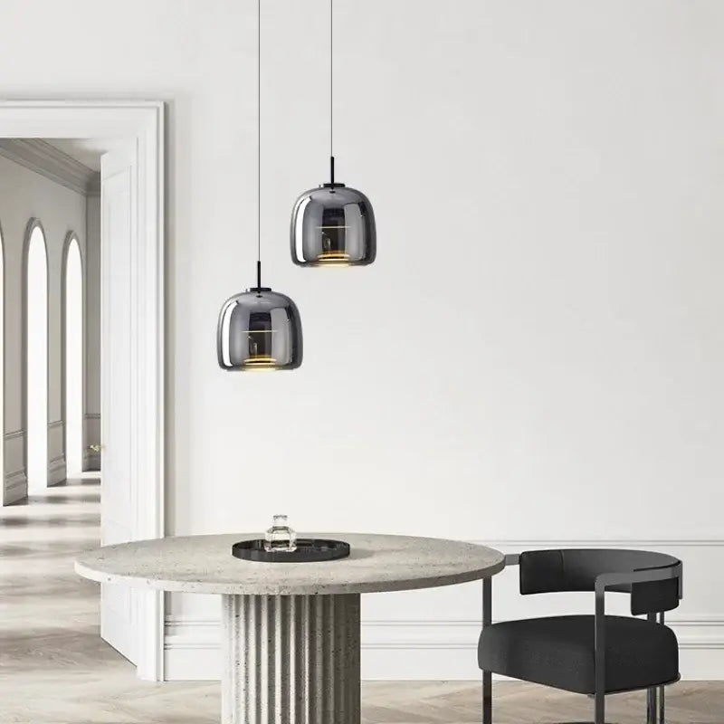 Two sleek dark gray glass DecorBites™ Moroccan Amber modern nordic pendant lights hang above a concrete table