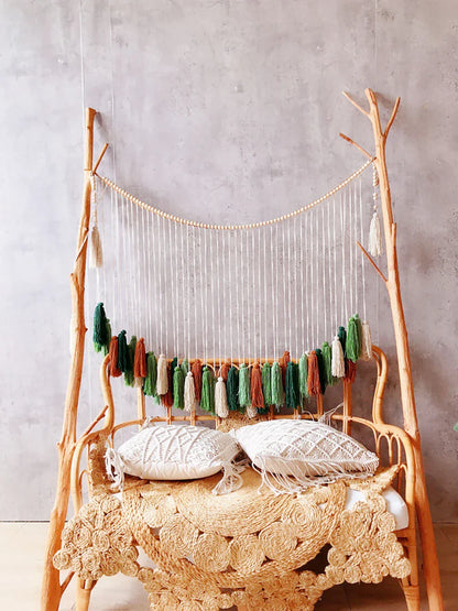 A rustic wooden frame featuring a moroccan bohemian wall decor tapestry with colorful macrame tassels in green orange and cream