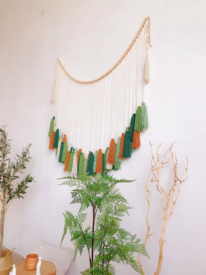 A moroccan bohemian wall decor tapestry featuring a curved wooden bead arch with white green and orange tassels