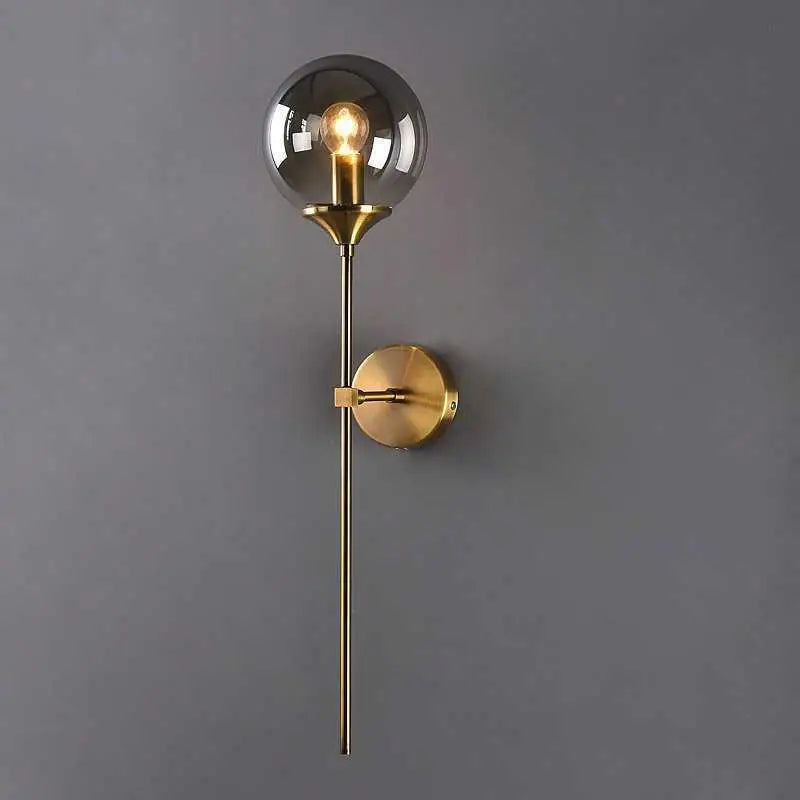 A sleek brass decorbites™ moroccan glass wall sconce with a smoked glass globe and exposed filament bulb