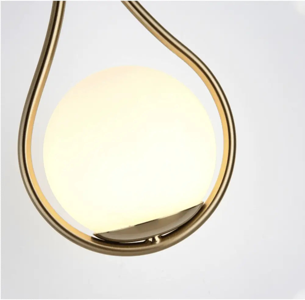 Decorbites™ moroccan gold modern nordic wall lamp with a curved gold metal frame and frosted glass globe emitting warm light
