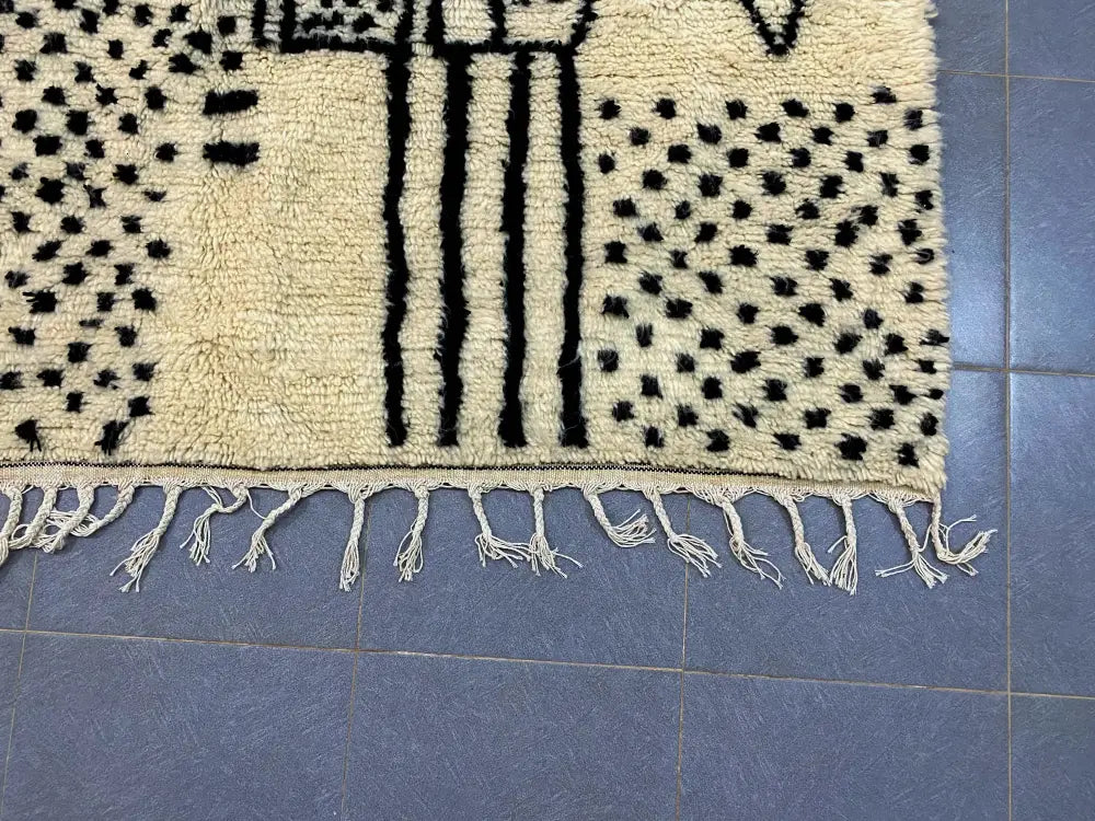 Cream-colored moroccan handmade azilal rug with black geometric patterns and fringed edges by DecorBites™ 3m x 2m