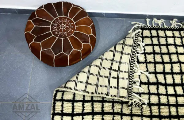 Brown leather pouf with stitched geometric patterns complementing moroccan handmade beni ouarain rug decor