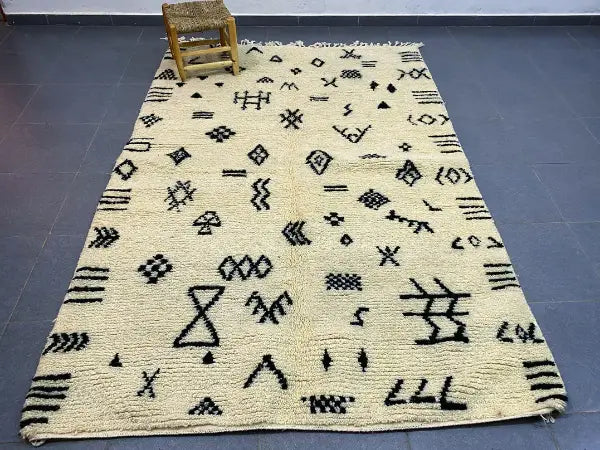 Cream-colored beni ouarain moroccan handmade rug with intricate black geometric patterns and fringed edges 2.5m x 1.5m
