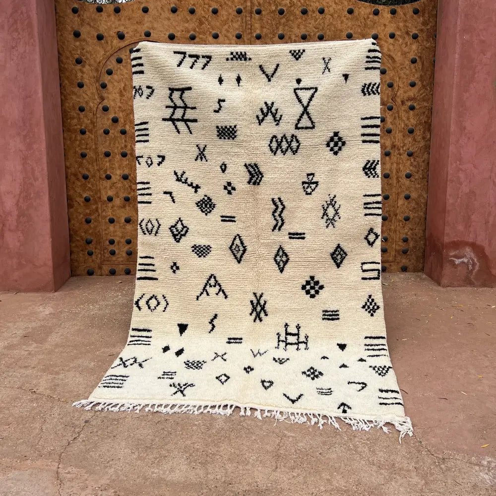 Cream-colored beni ouarain moroccan handmade carpet with black geometric patterns and fringed edges 2.5m x 1.5m