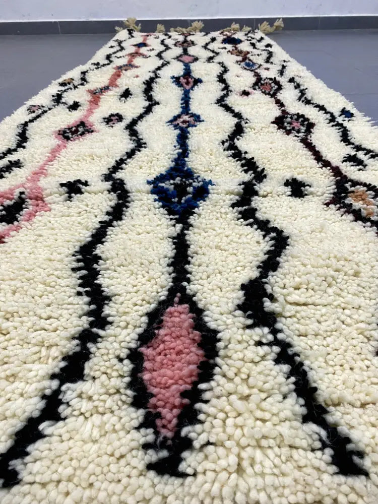 Cream-colored moroccan handmade beni ouarain rug with bold black pink and blue geometric patterns in plush wool