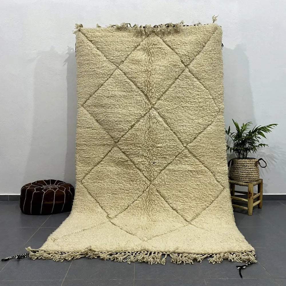 Cream-colored thickly woven moroccan handmade beni ouarain rug with diamond pattern and fringed edges by decorbites