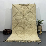 Cream-colored thickly woven moroccan handmade beni ouarain rug with diamond pattern and fringed edges by decorbites