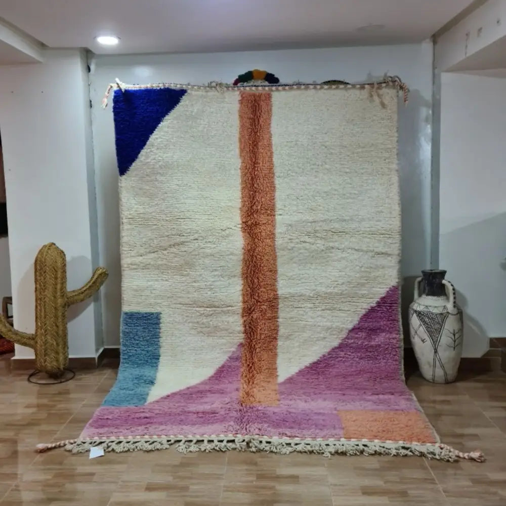 A vibrant moroccan handmade beni ouarain rug with geometric patterns in blue orange purple pink and wool fringed edges