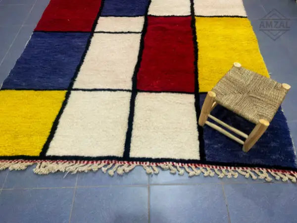Vibrant moroccan handmade beni ouarain wool rug with geometric red blue yellow and cream squares bordered in black
