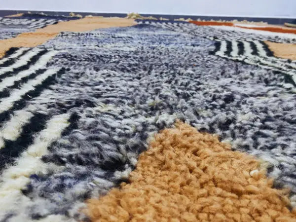 A plush moroccan handmade beni ouarain rug with bold gray black white and tan geometric stripes by decorbites
