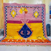 Vibrant pink and yellow moroccan handmade beni ouarain rug with a bold blue diamond motif and intricate geometric borders