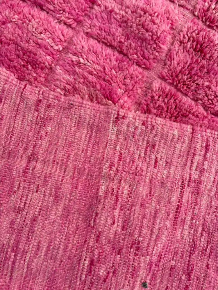 A plush pink towel with quilted pattern and woven border complementing the moroccan handmade beni ourain rug