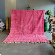 A vibrant fuchsia decorbites moroccan handmade beni ourain rug with textured hand-knotted weave and fringed edges