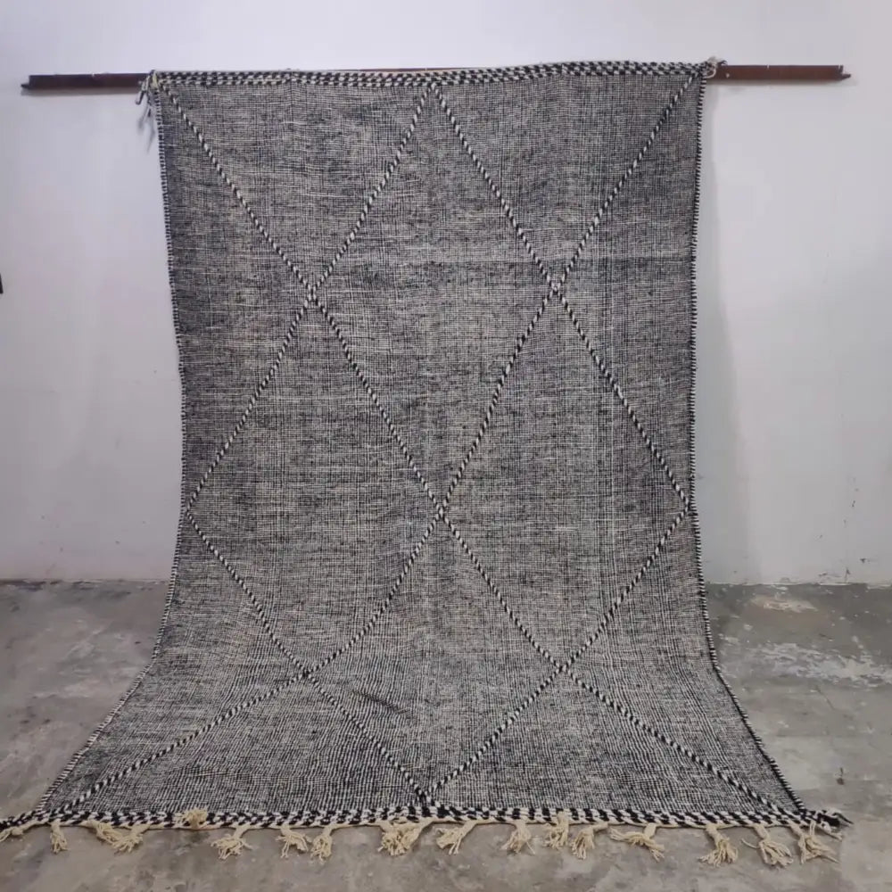 A handwoven gray and black moroccan handmade custom hanbel rug with diamond pattern and fringed natural fiber texture