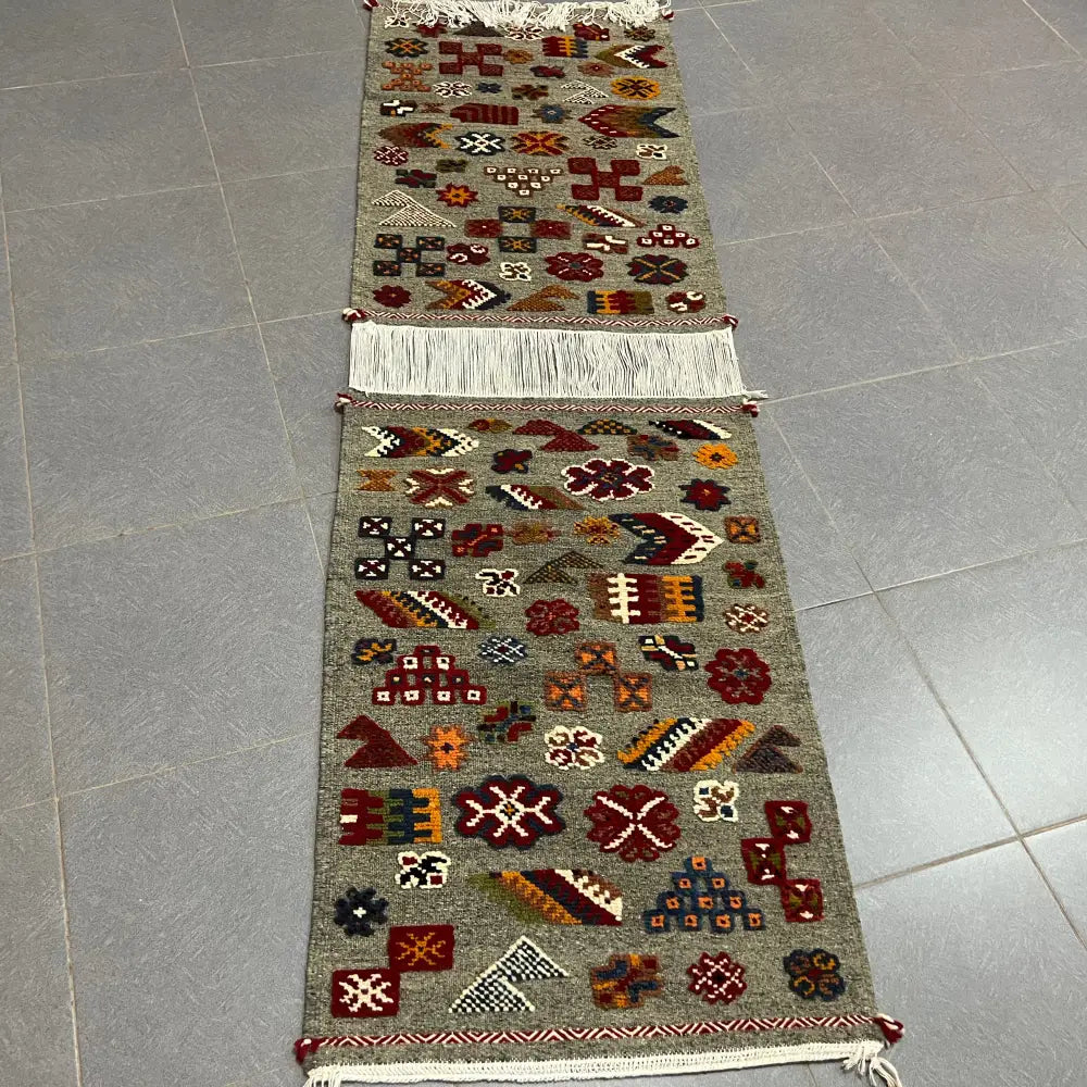 A handwoven gray moroccan handmade taznakht rug with intricate red floral and geometric patterns and fringed edges