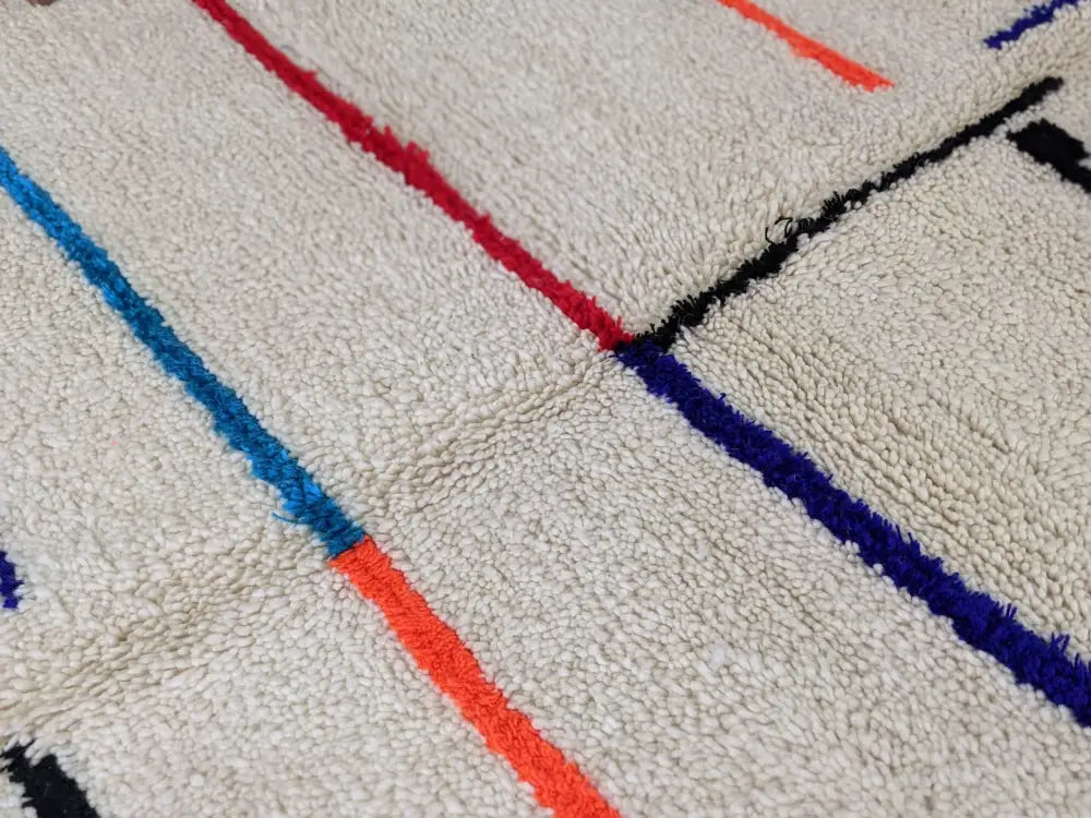 Cream-colored moroccan handmade azilal rug with bold red blue orange and black geometric stripes in pure natural wool
