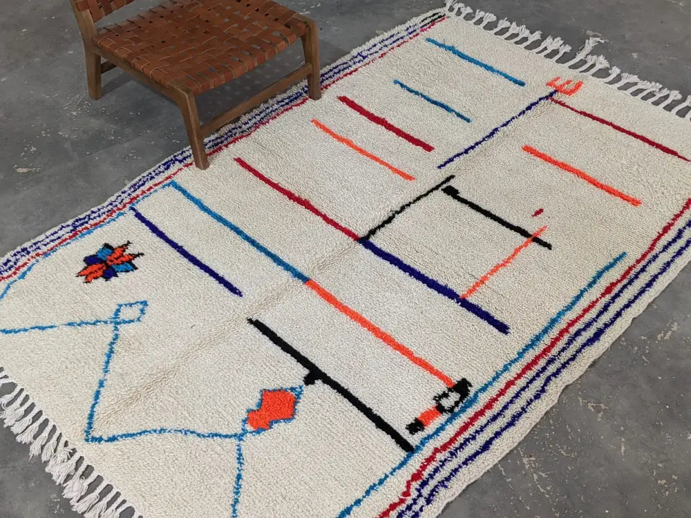 Cream-colored moroccan handmade azilal rug with bold blue red and black geometric patterns in pure natural wool