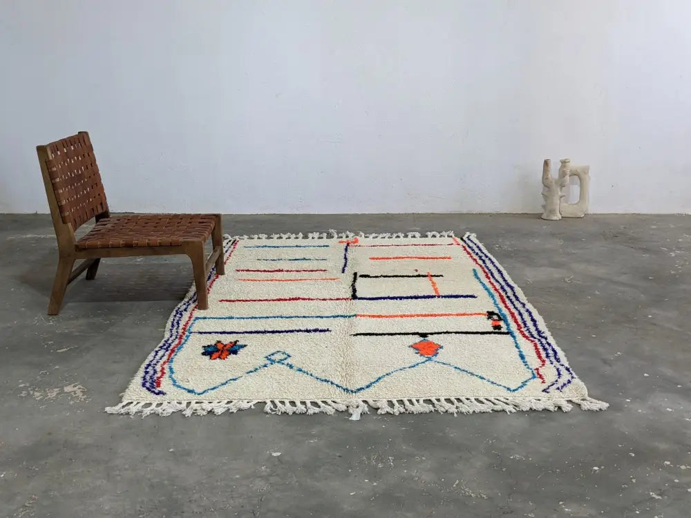 Cream-colored moroccan handmade azilal rug with geometric blue red and orange patterns in pure natural wool 231 x 160 cm