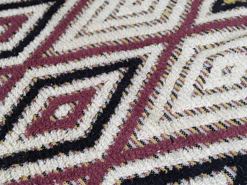 A plush moroccan handmade traditional azilal rug with maroon black and cream geometric pattern and intricate details