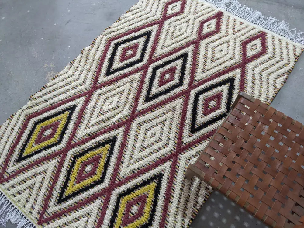 Moroccan handmade traditional azilal rug by decorbites with cream base, red black diamond pattern, yellow centers, and white fringe
