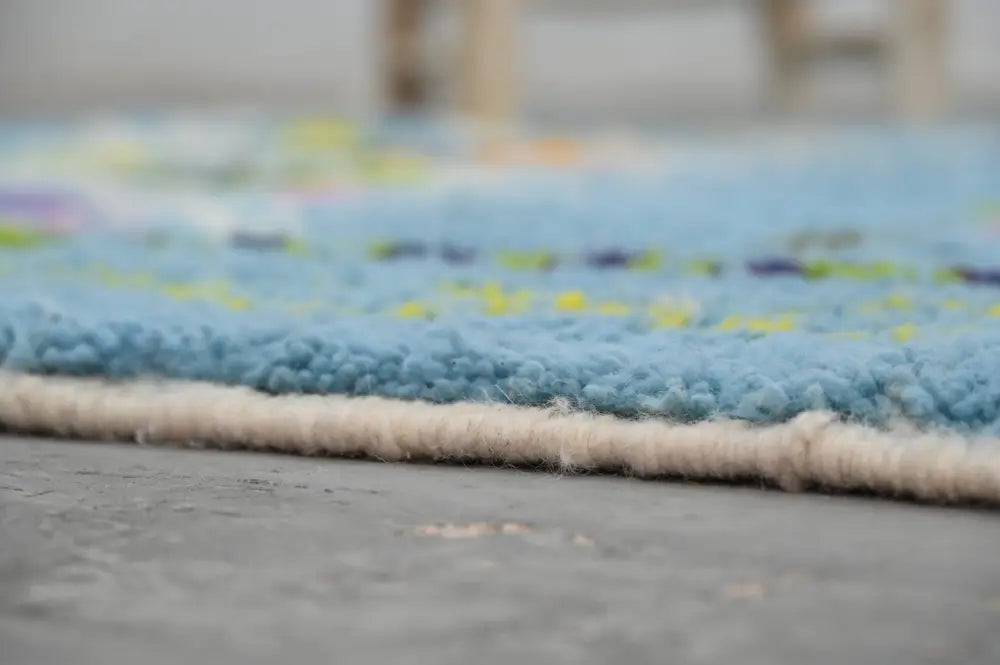 A soft blue shaggy moroccan handmade traditional azilal rug with cream border and yellow, purple, green accents