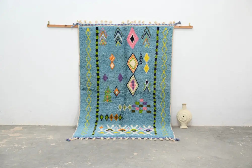A vibrant blue moroccan handmade traditional azilal rug with colorful geometric patterns and tassels by decorbites