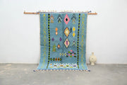 A vibrant blue moroccan handmade traditional azilal rug with colorful geometric patterns and tassels by decorbites