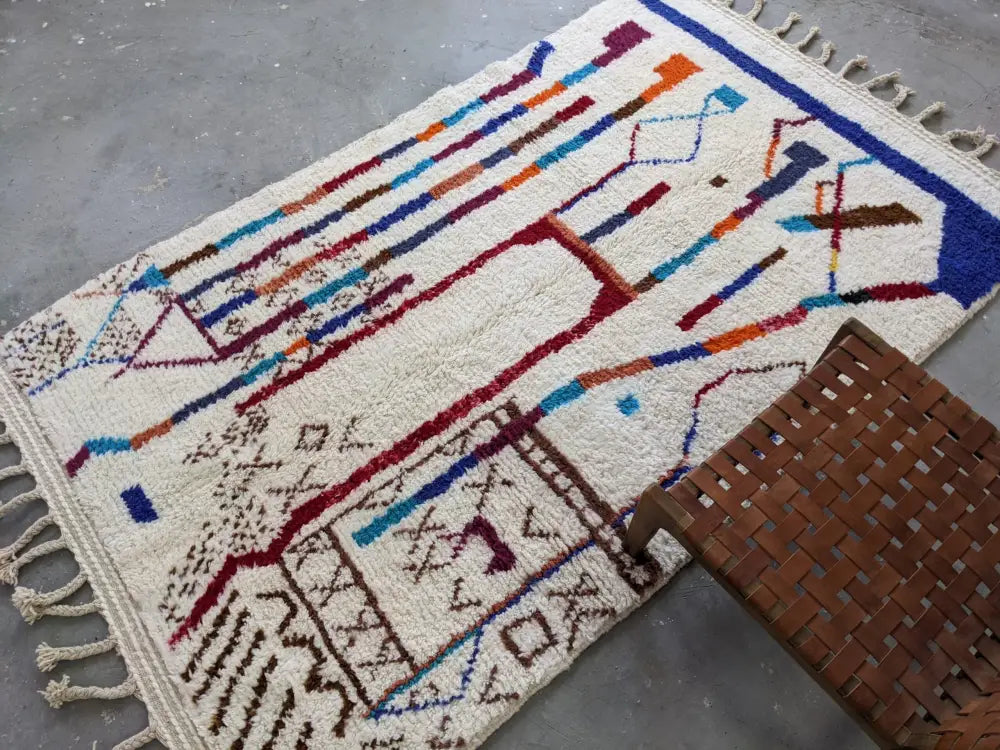 Cream-colored moroccan handmade traditional azilal rug with vibrant geometric patterns on textured wool base 250 x 150 cm