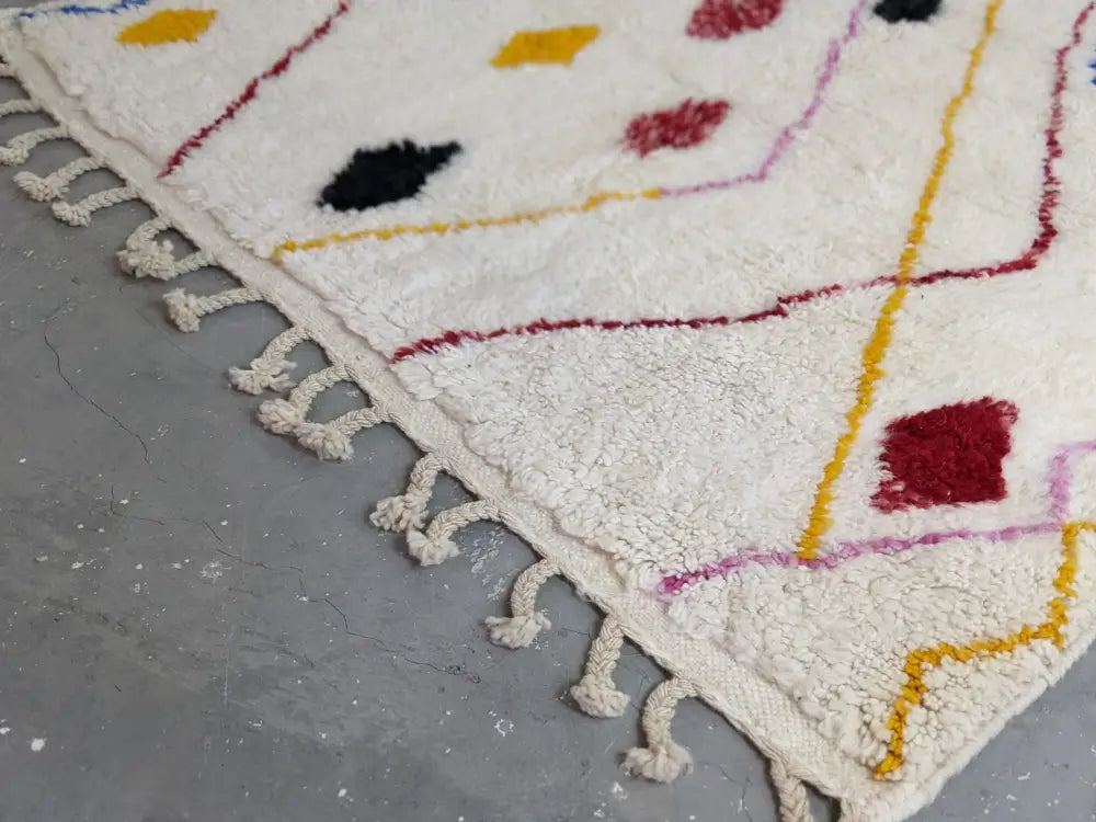 Cream-colored moroccan handmade traditional azilal rug with textured hand-knotted surface and colorful geometric patterns