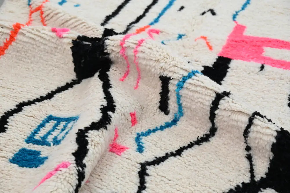 Cream-colored plush wool moroccan handmade traditional azilal rug with bold black pink and blue geometric patterns