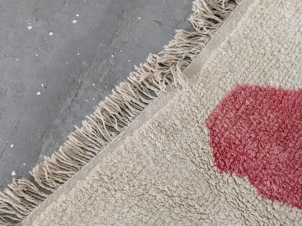 Beige plush decorbites moroccan handmade traditional azilal rug with textured red circular design and natural fiber fringe