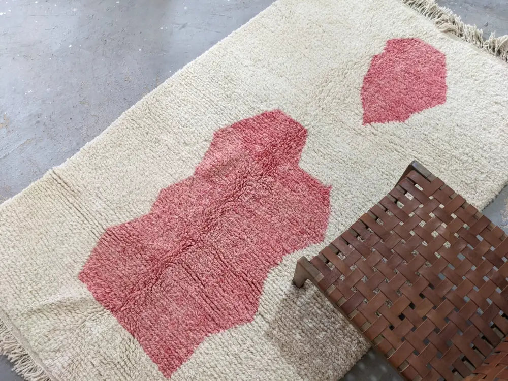 Cream-colored wool moroccan handmade traditional azilal rug with two abstract pink patches and fringed edges 255 x 155 cm