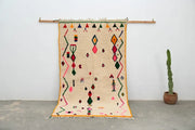 Beige moroccan handmade traditional azilal rug with vibrant pink green orange and red geometric patterns on woolen surface