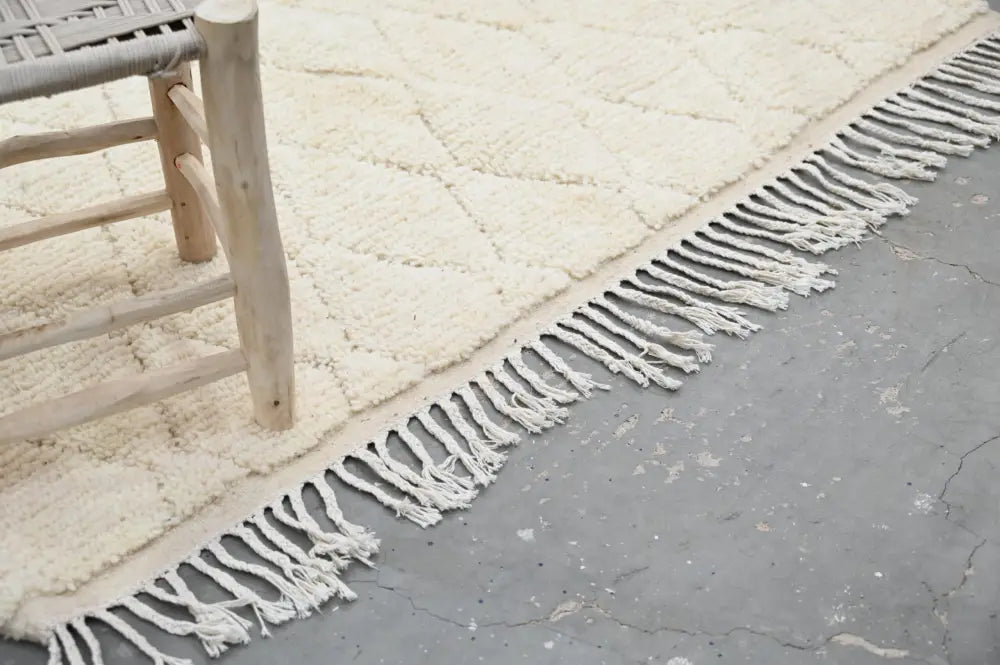 Cream-colored moroccan handmade traditional azilal rug with diamond pattern and long fringed edges by decorbites