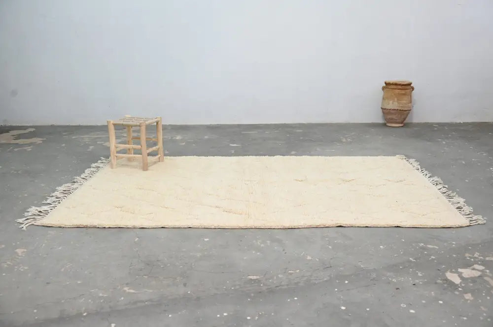 Cream-colored moroccan handmade traditional azilal rug with fringed edges and textured surface by decorbites
