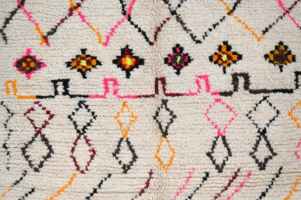 Cream-colored moroccan handmade traditional azilal rug with vibrant pink orange black and maroon geometric patterns