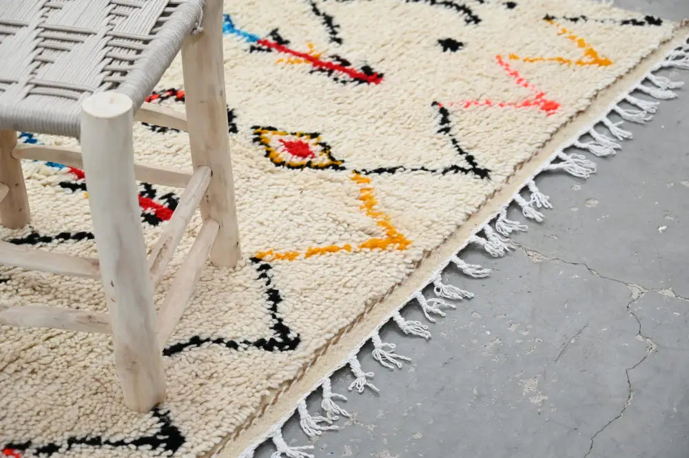 Cream-colored moroccan handmade traditional azilal rug with bold geometric patterns and fringed edge by decorbites