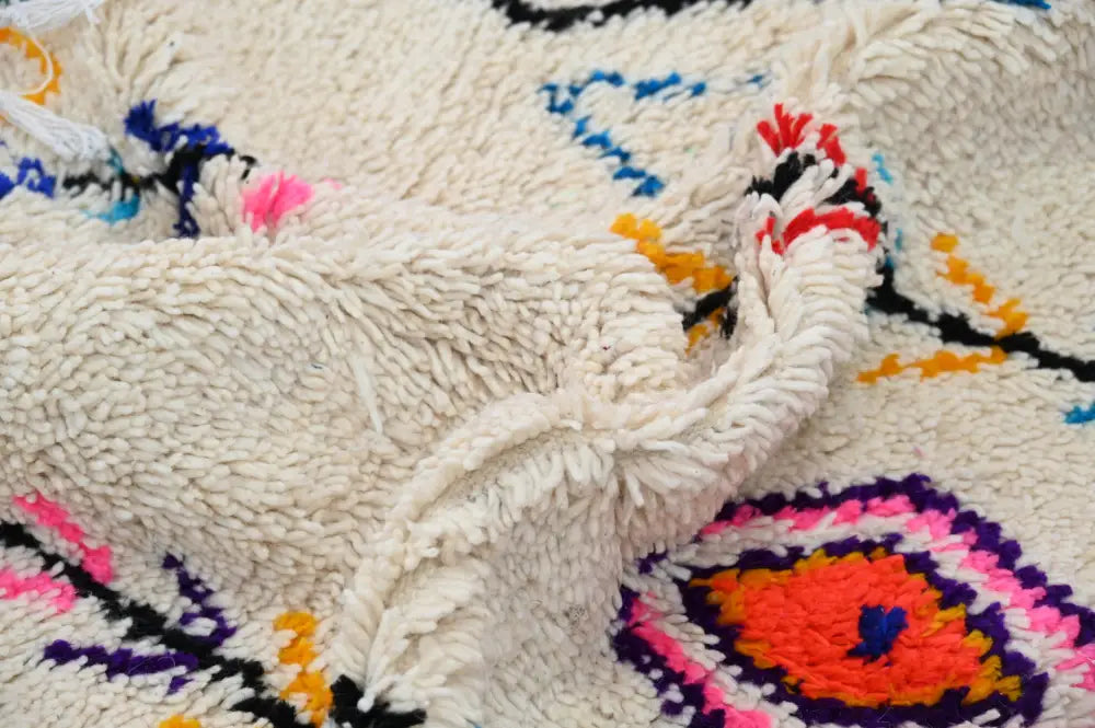 Cream-colored plush wool moroccan handmade traditional azilal rug with vibrant pink orange purple and blue geometric patterns