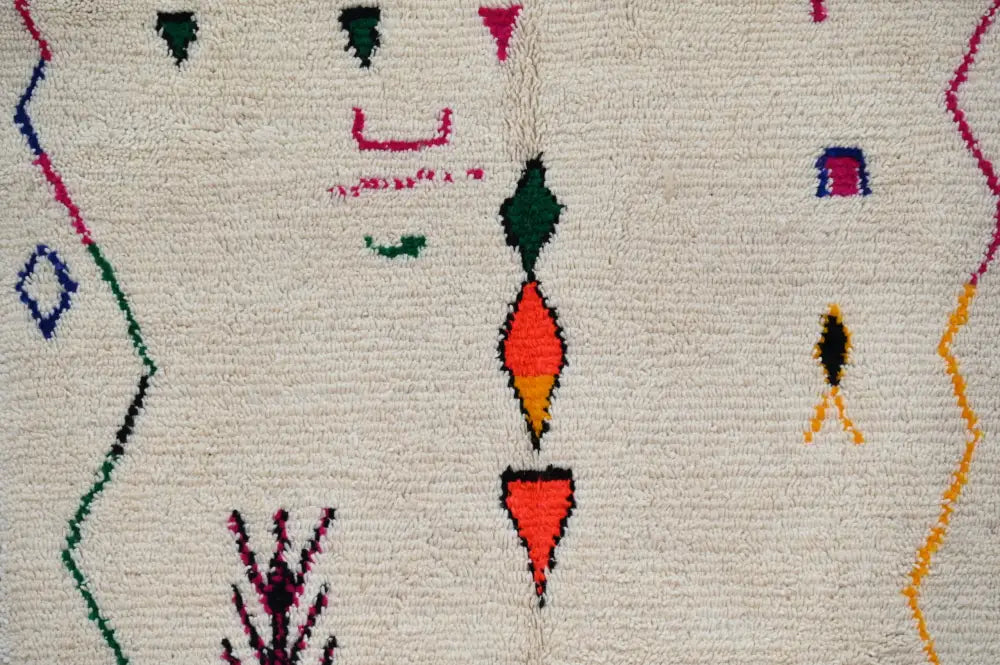 Cream-colored moroccan handmade traditional azilal rug featuring vibrant red green blue and yellow geometric patterns