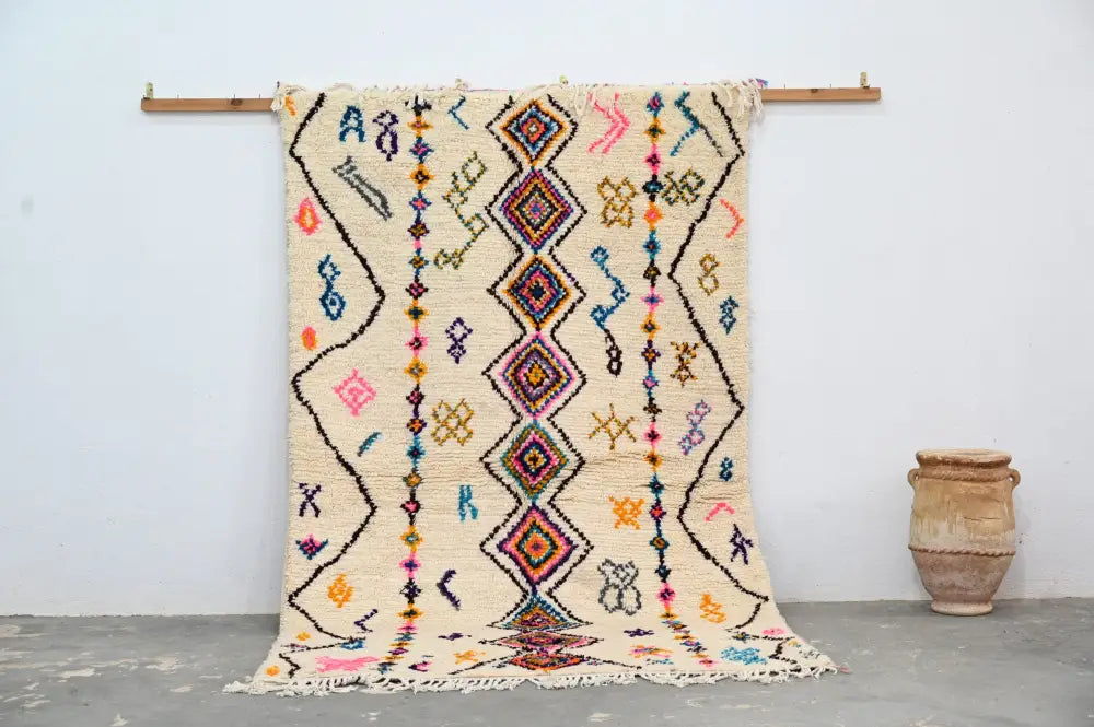 A vibrant cream-colored decorbites™ moroccan handmade traditional azilal rug with geometric patterns in bold hues