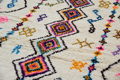 Cream-colored DecorBites™ moroccan handmade traditional azilal rug with vibrant pink blue yellow and purple geometric patterns