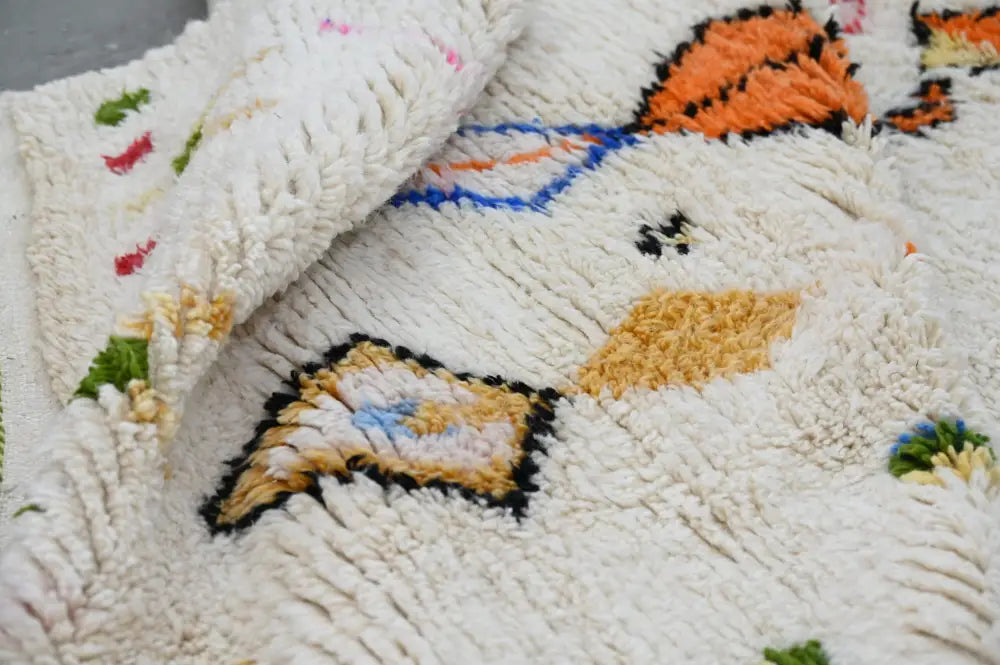 A plush off-white moroccan handmade traditional azilal rug with textured shaggy surface and vibrant geometric patterns