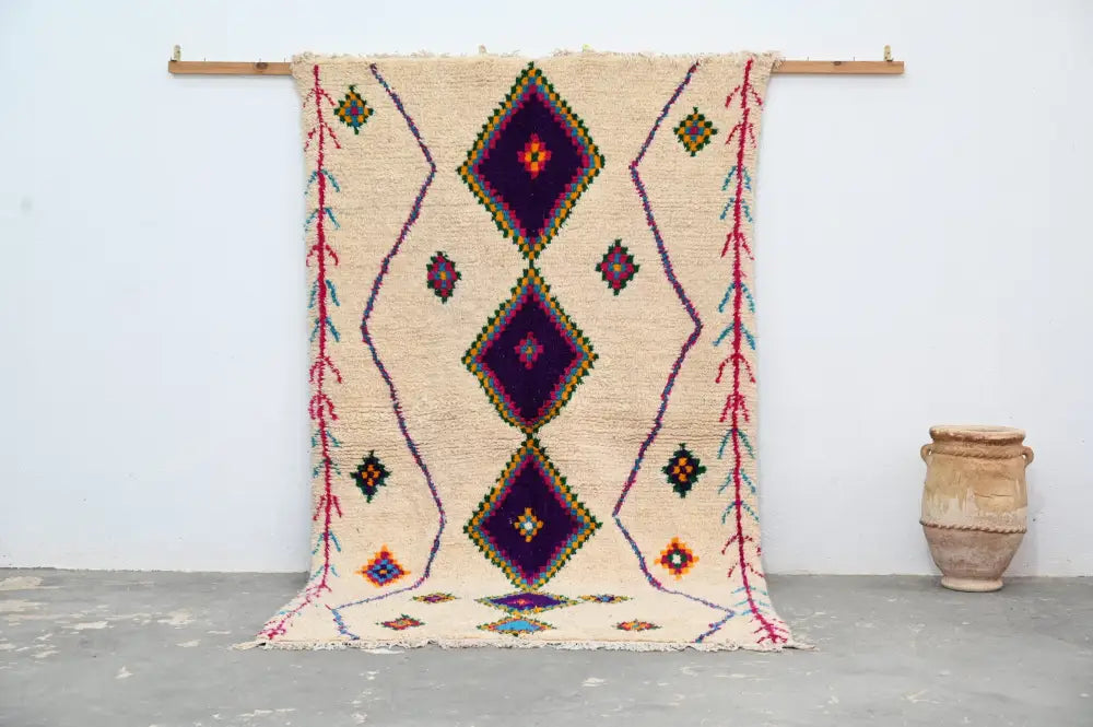 Beige moroccan handmade traditional azilal rug with bold purple diamond patterns and colorful geometric accents by DecorBites