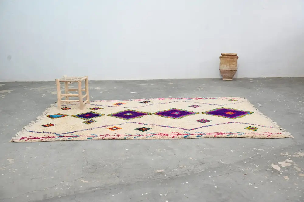 Cream-colored moroccan handmade traditional azilal rug with bold purple diamond patterns and colorful geometric accents